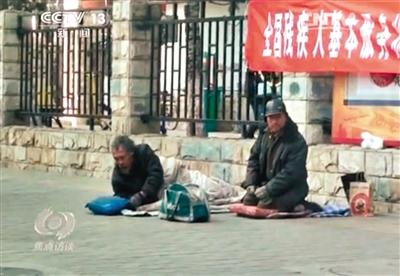 工人體育場北路，兩位乞討者路邊乞討，并輪流扮成“病人”（躺地者）。 央視截圖