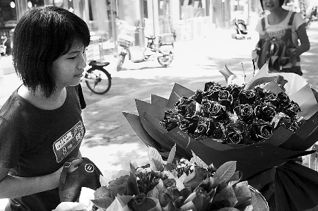 鄭州市農(nóng)業(yè)路一家花店擺放的玫瑰花吸引著一位過往女孩。