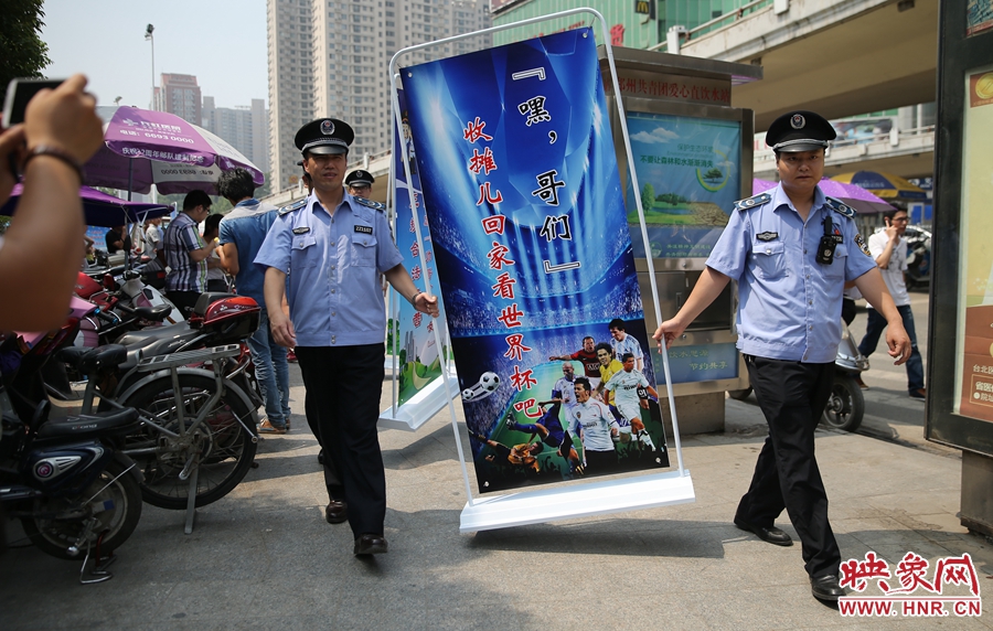 7月2日上午，鄭州市紫荊山地鐵站出入口，執(zhí)法人員抬著寫(xiě)有勸導(dǎo)語(yǔ)的宣傳板，前往占道經(jīng)營(yíng)攤位“圍觀執(zhí)法”