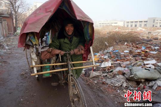 圖為老人走出窩棚，推著三輪車準備出去撿拾廢品。周小云 攝